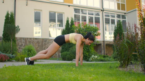 a woman in a city park does an exercise climber on the grass in slow motion. exercise climber on the grass for abdominal muscles.