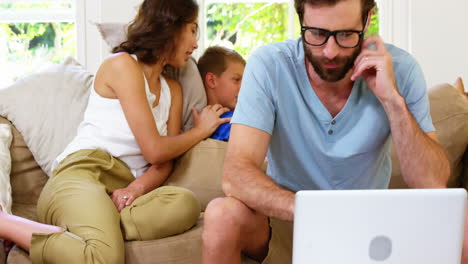 Concentrated-father-in-front-of-mother-and-son-sitting-on-a-sofa