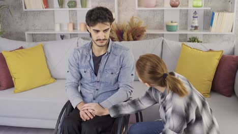 Woman-holding-hand-of-disabled-boyfriend-sitting-in-wheelchair.