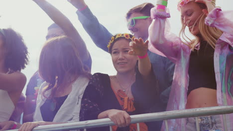 group of young friends dancing behind barrier at outdoor music festival