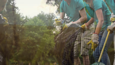 Animation-of-grass-over-senior-caucasian-man-and-young-women-collecting-rubbish-in-forest