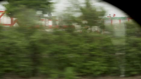 blurry greenery and buildings seen from a moving train, evoking a sense of speed and travel, overcast day