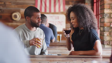 young couple meeting in sports bar enjoying drink before game