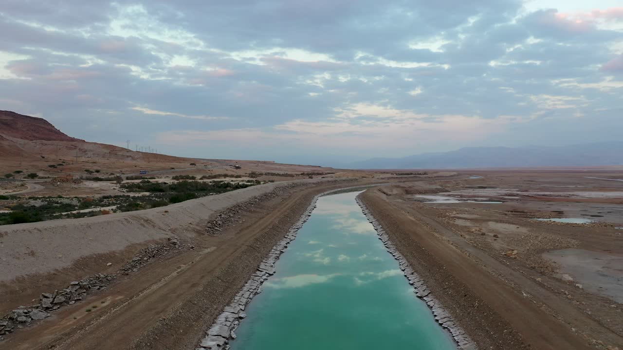 israel, canal de agua de color turco por el reflejo del cielo del mar muerto, movimiento de drones disparado hacia adelante y hacia arriba