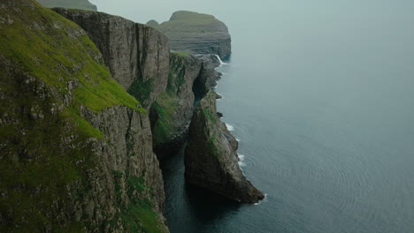 Majestic Green Cliffs Meeting the Ocean Under an Overcast Sky