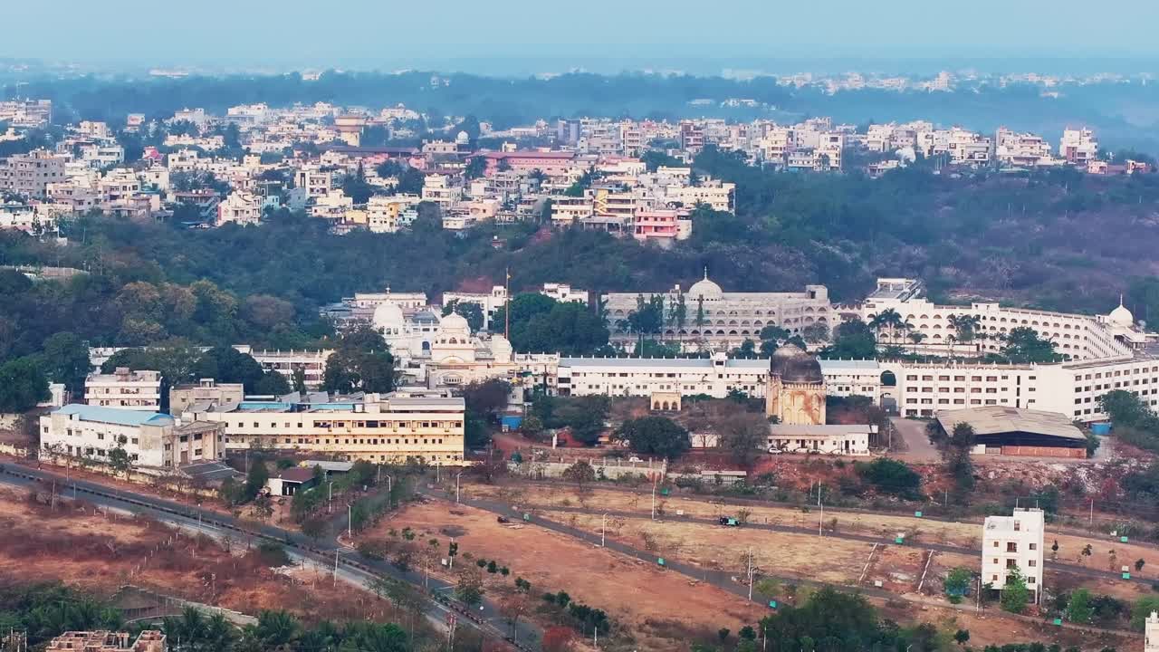 Gurudwara Sri Nanak Jhira Sahib con vegetazione, nebbia ed edifici a Bidar, Karnataka, India. Ripresa diurna, tilt up, allontanamento e drone, 4k.