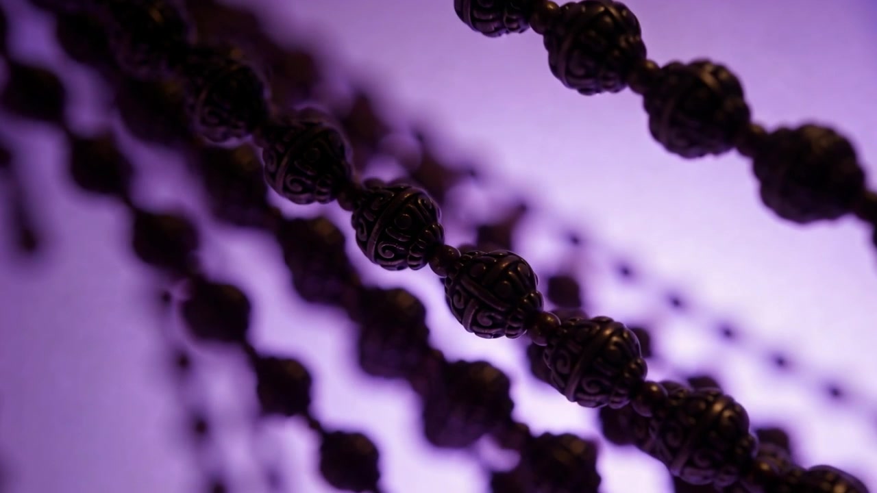 Ajuste de foco fazendo com que correntes de contas ornamentadas se movam diagonalmente através de um painel de LED roxo, criando efeito bokeh.