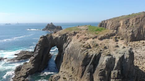 Enys-Dodnan-Arch-along-the-breathtaking-stretch-of-coastline-at-Land's-End,-Cornwall-during-a-warm-sunny-day