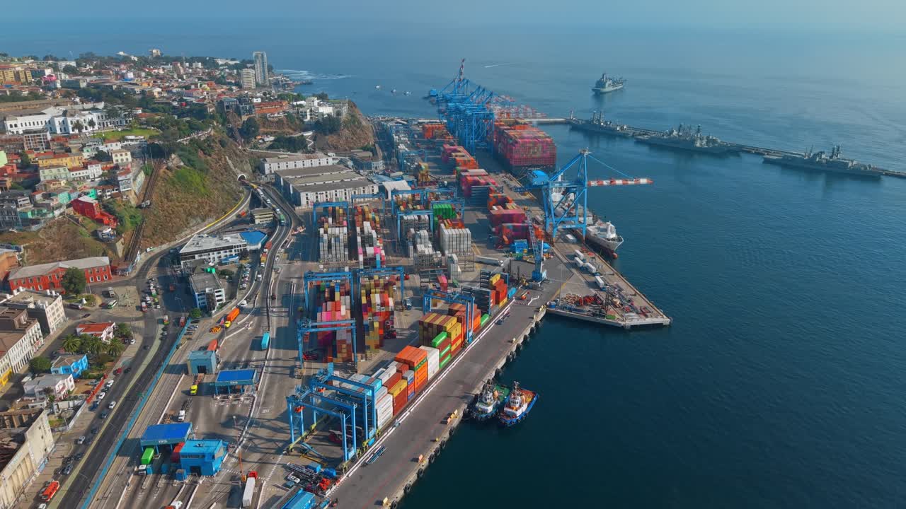 Establishing aerial view of the main port of Valparaíso on a sunny day with loaded containers and heavy machinery, Chile