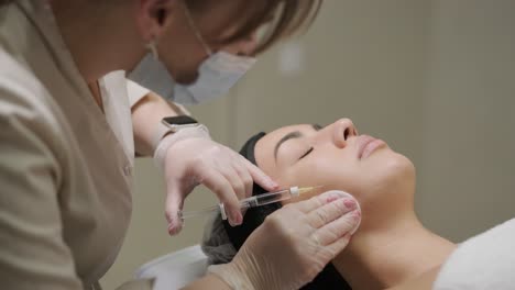 un paciente se reclina mientras recibe una inyección facial de un clínico en un entorno de spa médico, destacando el tratamiento estético sin centrarse en marcas específicas