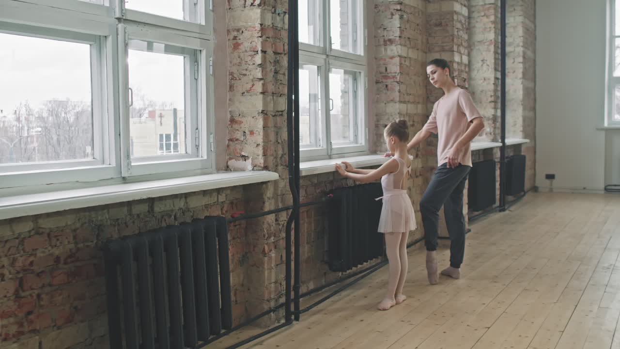 Liten jente som tøyer seg på ballettklasse