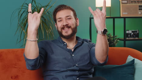 overjoyed young lebanese man showing rock n roll gesture, cool sign dancing rejoicing in success