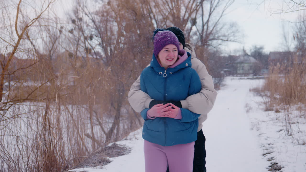 una pareja abrazándose en un parque nevado.