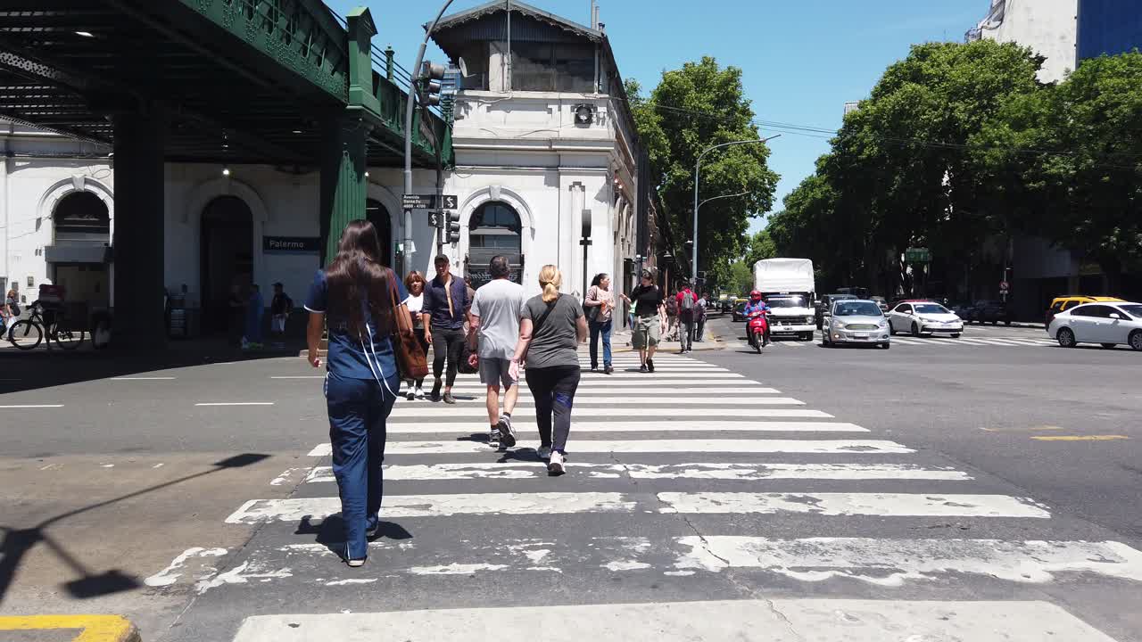 People crossing a city street on a sunny day