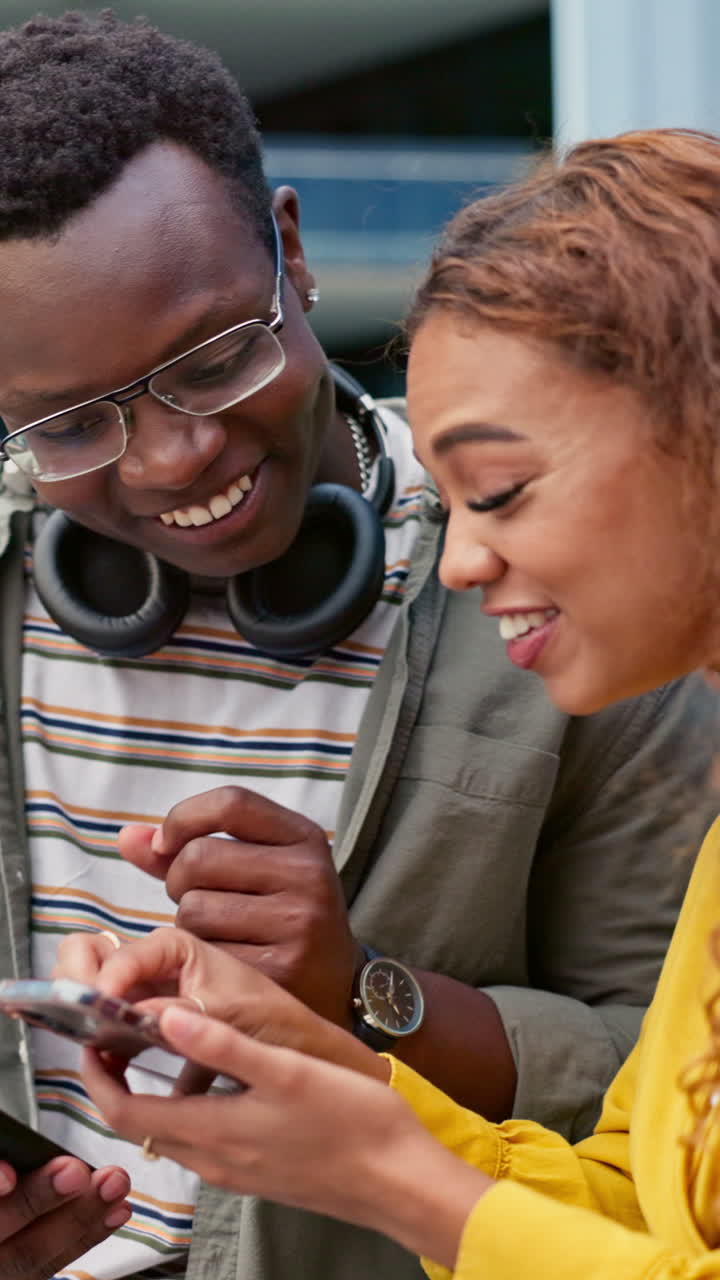Two people laughing while looking at a phone