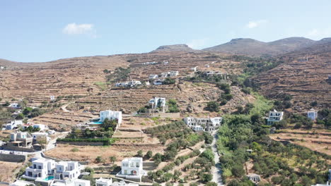 Vuelo-Aéreo-De-Drones-Hacia-El-Paisaje-Montañoso-Seco-Con-Pocas-Casas-Ubicadas-En-La-Colina-En-Tinos,-Grecia