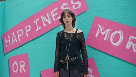 outdoor fashion portrait of young alternative style woman leaning in smiling into camera against graffiti covered walls of london city street uk in real time 1