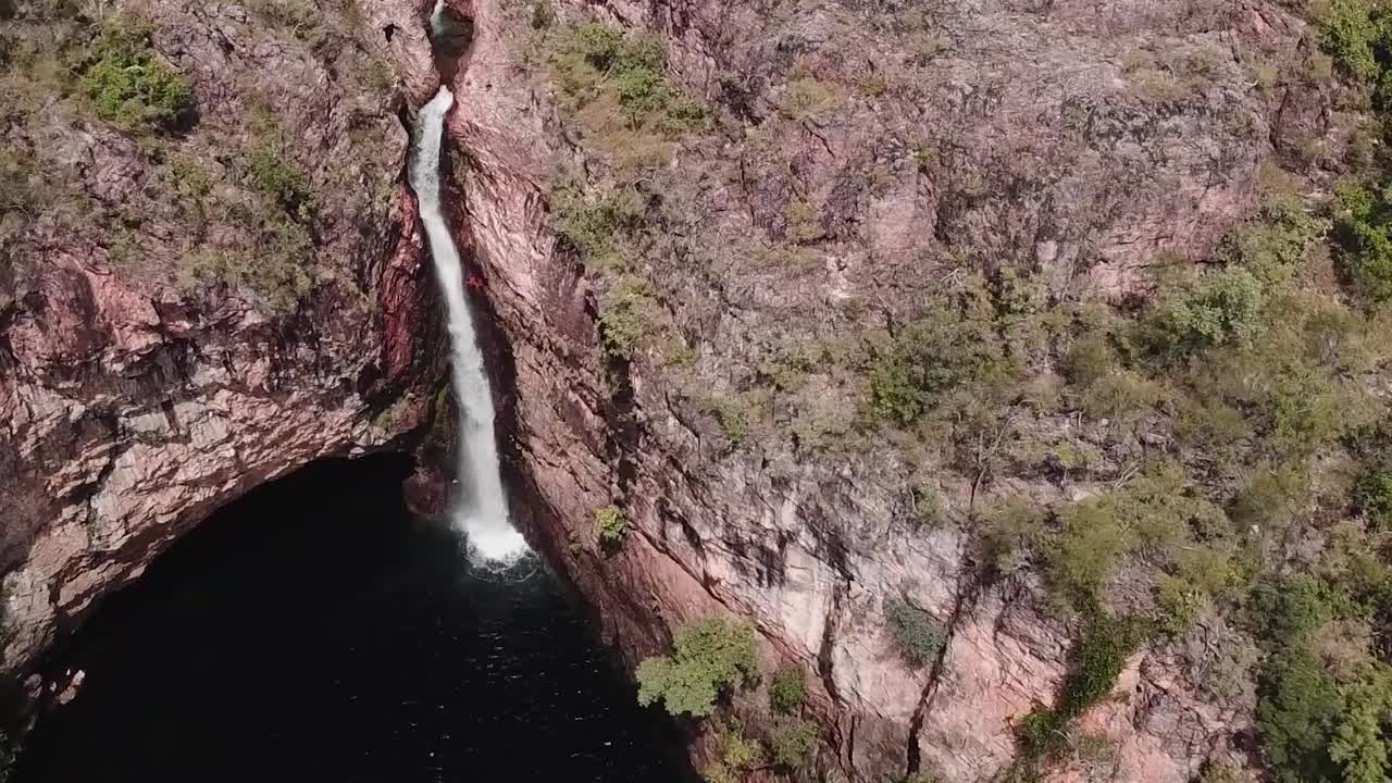 imágenes de drones de una cascada que fluye desde el borde del acantilado hacia un gran lago