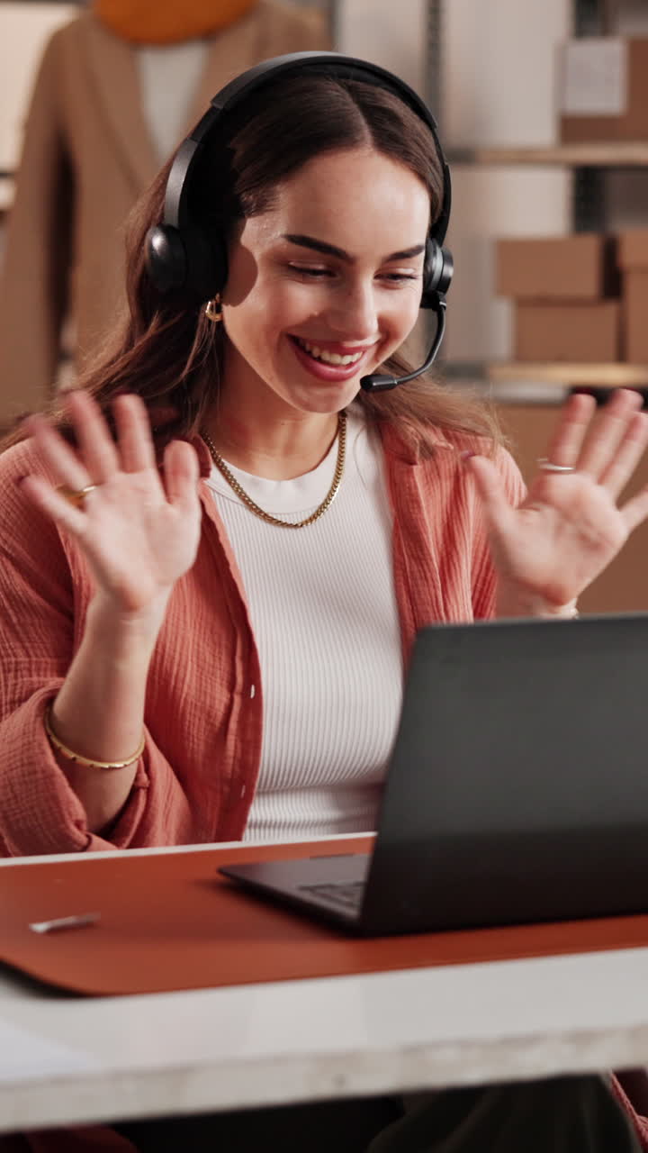 Joven feliz con auriculares saludando y escribiendo en laptop