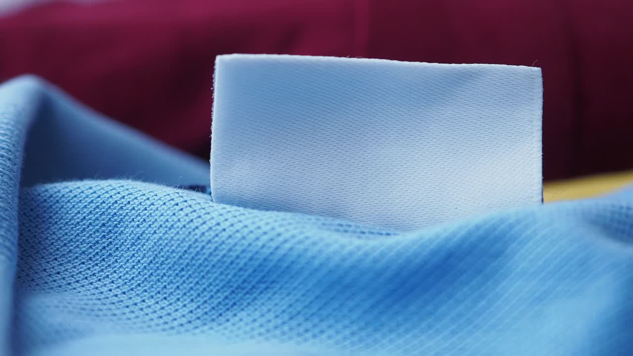 un primer plano de una etiqueta de tela en blanco en una camisa azul