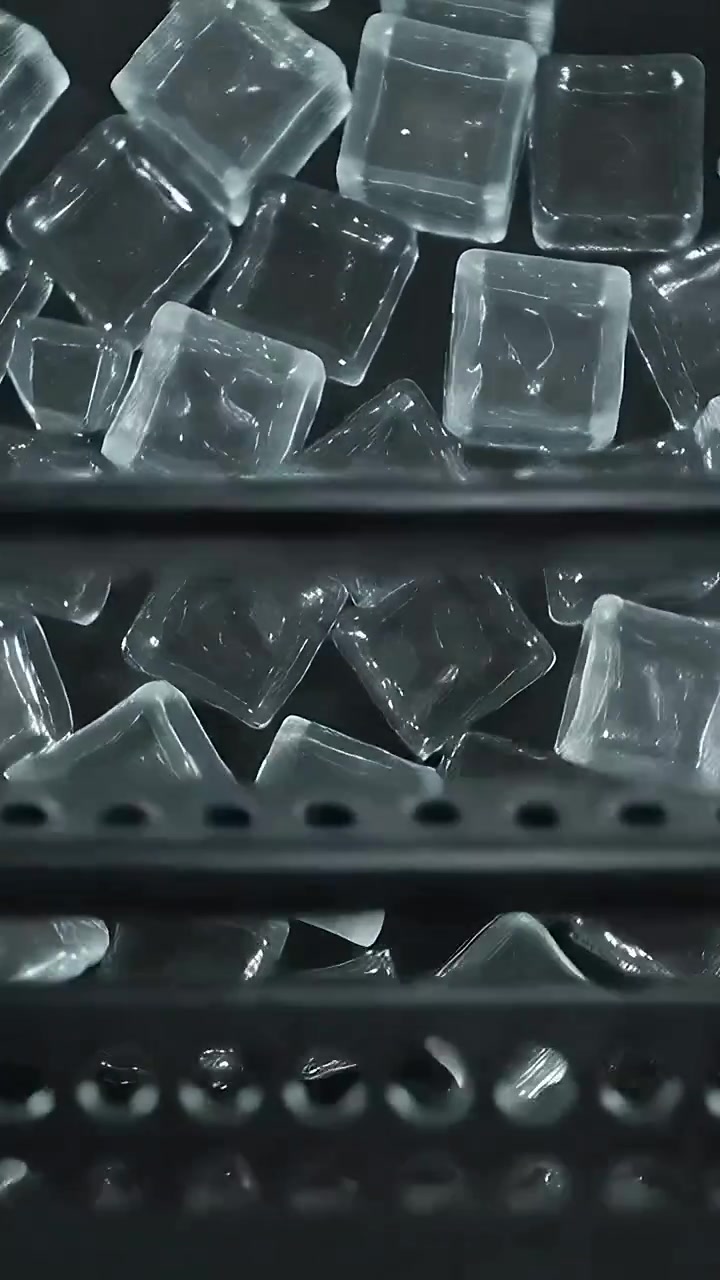 Video verticale: Vassoi forati che scendono in un contenitore di metallo, spostando leggermente dei cubi di vetro