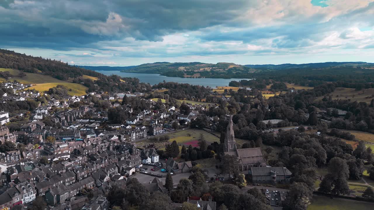 imágenes aéreas del tranquilo pueblo de ambleside, moviéndose lentamente hacia la iglesia de st mary y el lago windermere en la distancia