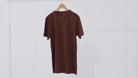 video of brown t shirt on hanger and copy space on white background