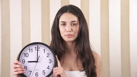 a close-up of a cute girl. the girl is holding a wall clock and moves the clock hand.