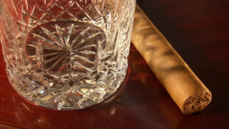 close up of empty crystal glass and cigar coming out of shadow