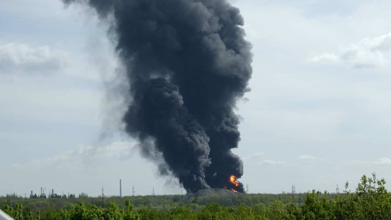 un fuego gigante y una columna de humo negro después de la explosión en el almacén de petróleo.