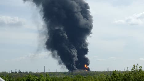 a giant fire and a column of black smoke after the explosion at the oil storage.