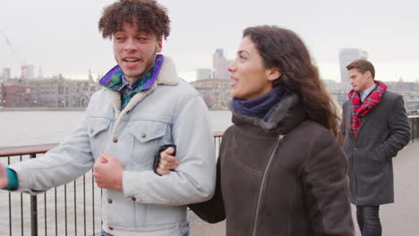 friends walking along south bank on winter visit to london