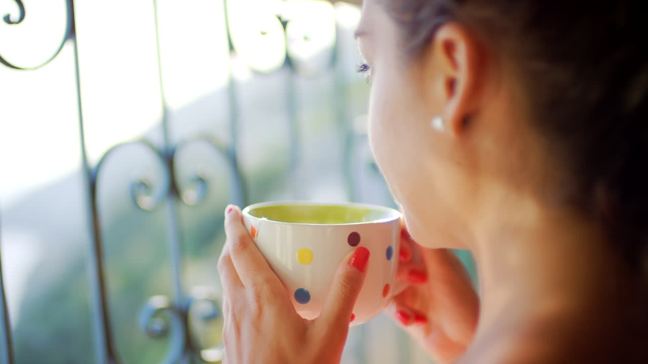 발코니 에서 커피 를 마시고 있는 여자