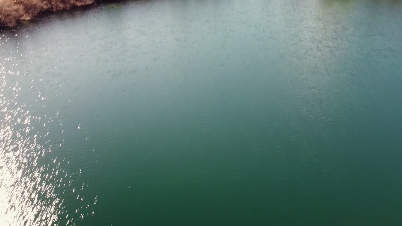 Drone aerial view in Spain flying forward from lake revealing snow mountain landscape Moncayo