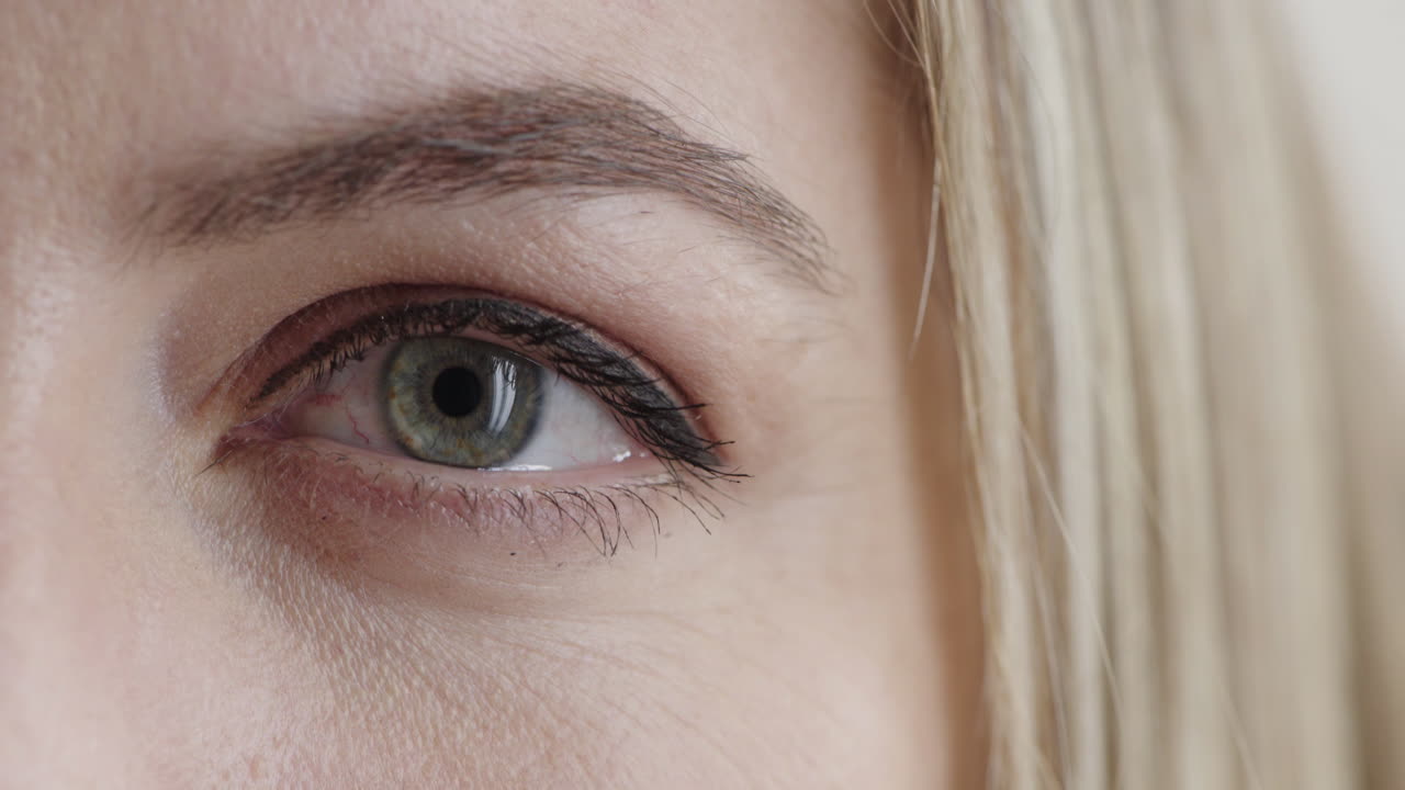 cerca del hermoso ojo azul de una mujer rubia mirando a la cámara