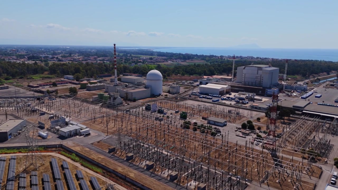 Riprese aeree con drone che catturano la centrale nucleare del Garigliano in Italia, evidenziando la cupola del reattore, la sottostazione elettrica e la posizione costiera