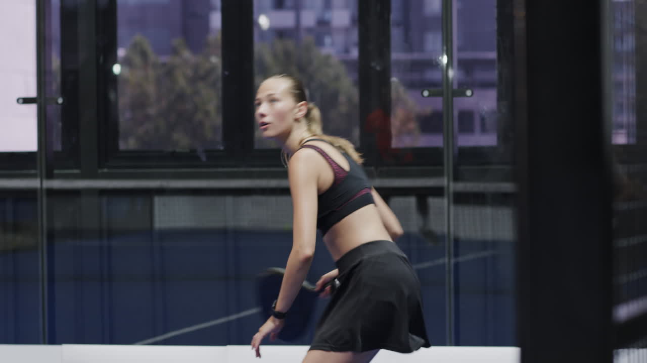 Focused woman playing padel tennis, preparing for intense match on court