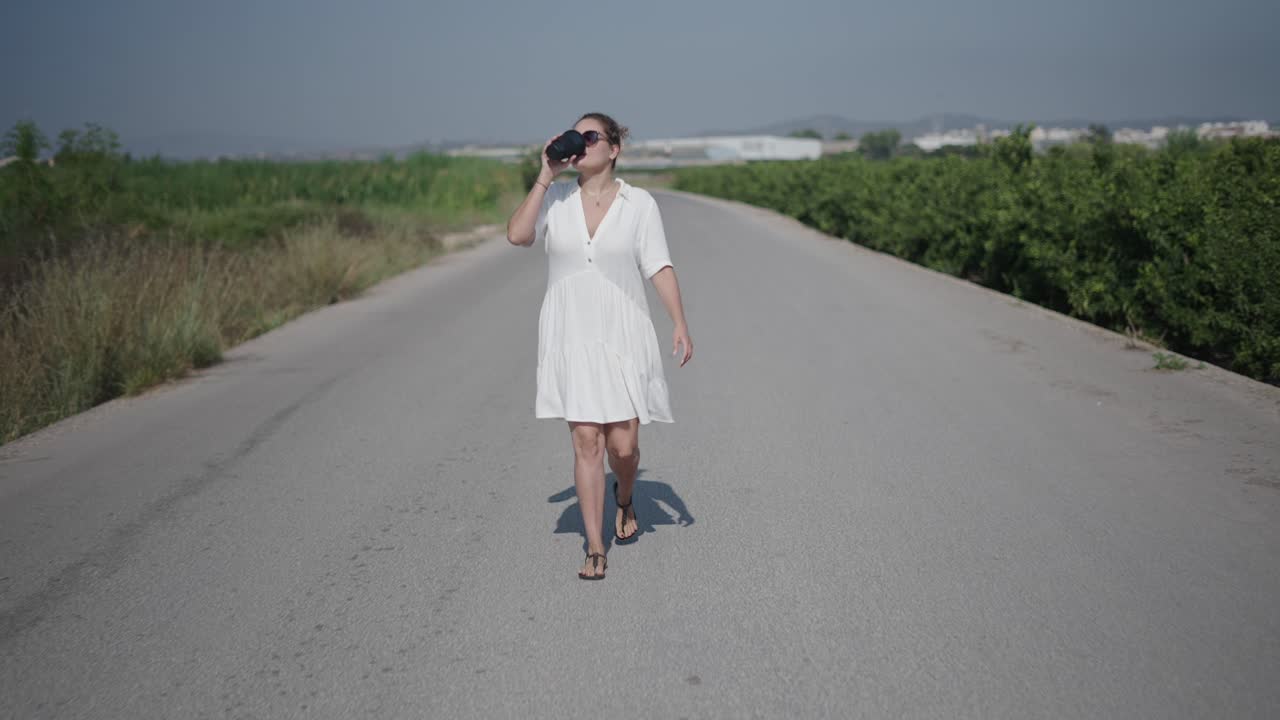 Woman Walking on a Road, Drinking Coffee