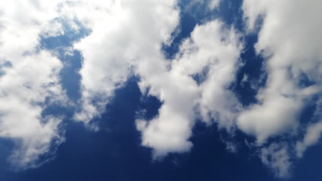 bright blue summer sky with quickly drifting clouds. white heavy cotton clouds floating blown by the wind.