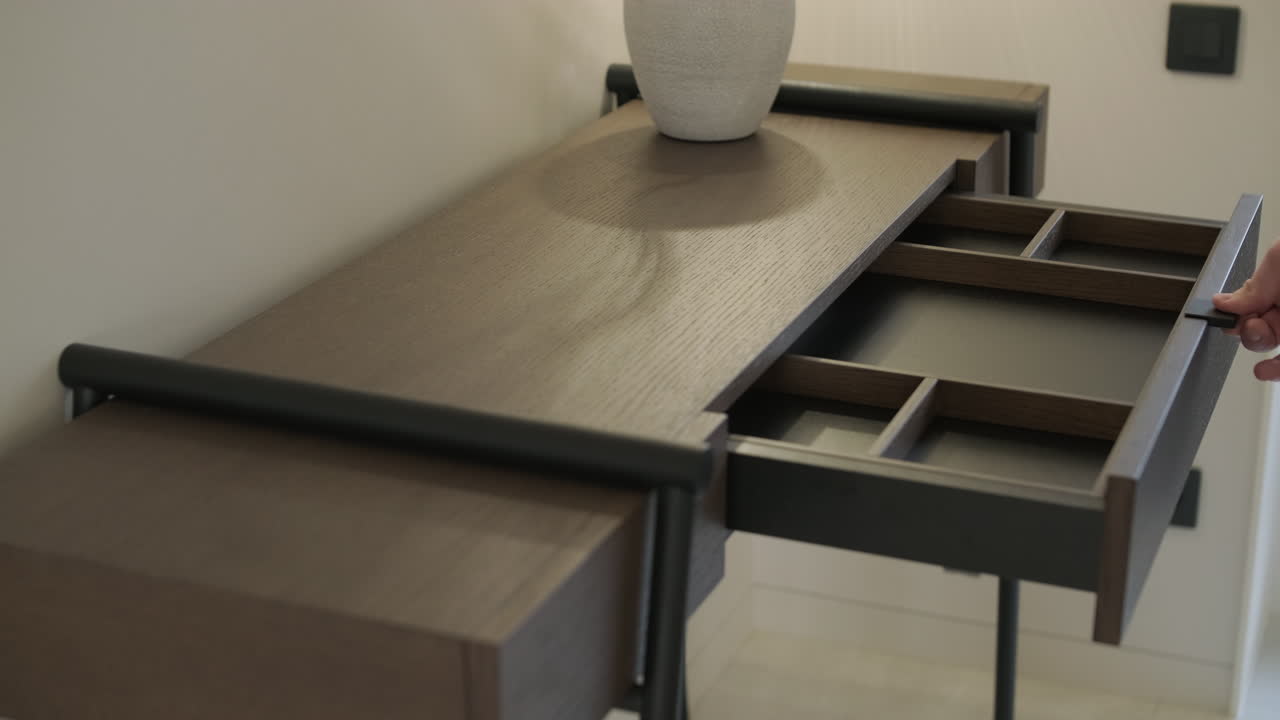 Mano che apre e chiude un cassetto di una consolle in legno moderna.