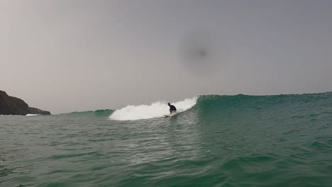 Surfer-man-riding-with-very-power-off-the-lip-on-the-beach-with-turquoise-water-and-waves-aerial-view