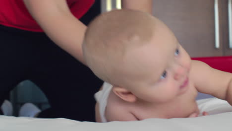 a woman playfully rolling a baby girl on a bed