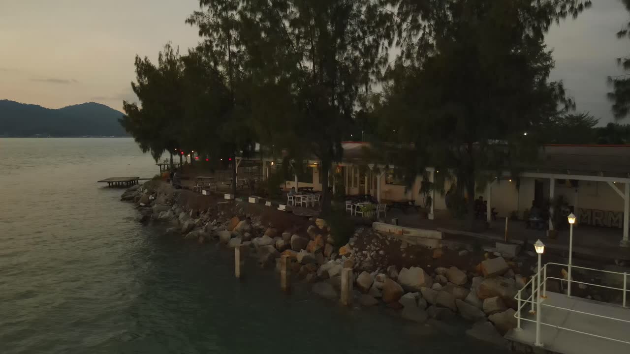 Ripresa con drone di una fila di alloggi fronte mare di sera, isola Marina, Malesia