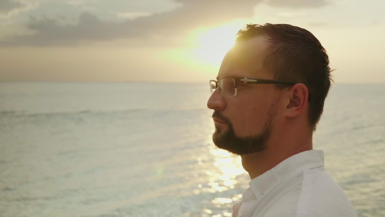 retrato de un joven en una playa tropical con una camisa fácil, sonríe y mira a la cámara wea