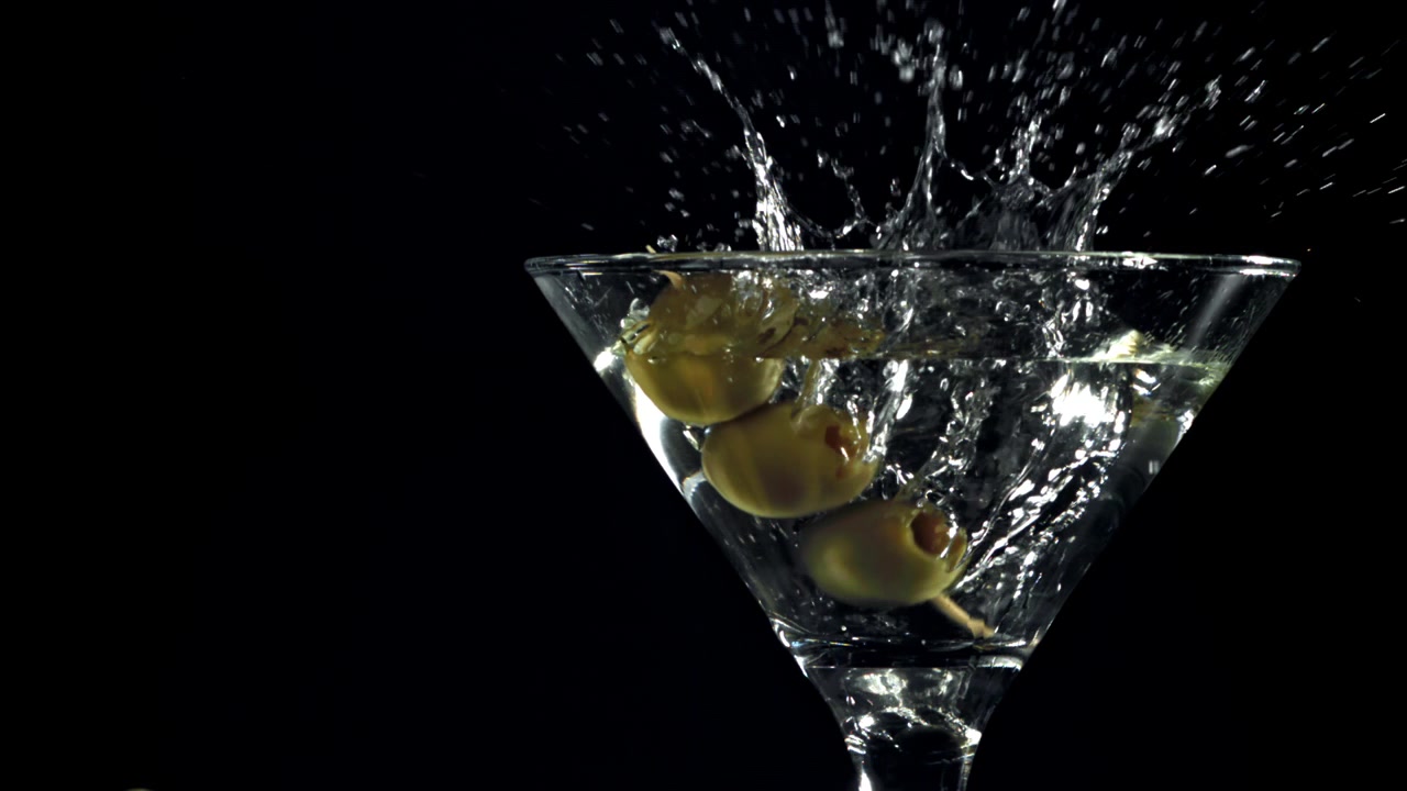 Olive Verdi che Schizzano in un Bicchiere da Martini su Sfondo Nero
