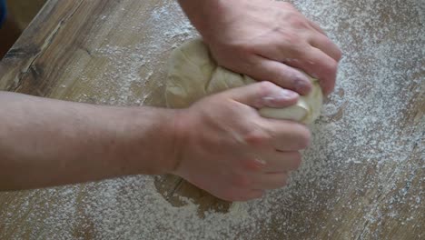 Kneading-dough-for-buns-by-hand-on-a-wooden-countertop