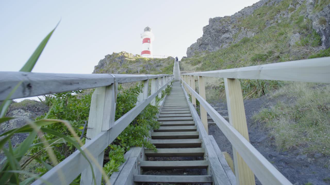 toma en perspectiva subiendo las empinadas escaleras de madera hacia un faro