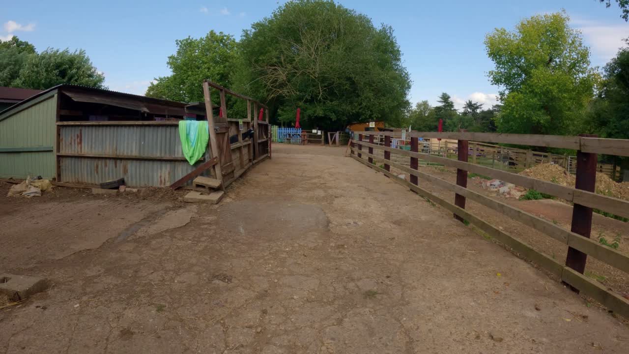 Point of view walking through farm yard in rural England, old barns and buildings UK Europe