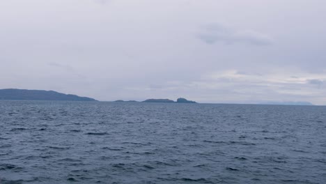 Scenic-landscape-view-of-rugged,-rocky-and-remote-Isle-of-South-Uist-and-ocean-from-passenger-ferry-in-the-Outer-Hebrides-of-Scotland-UK