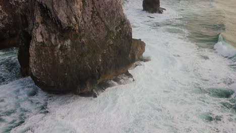 vista aérea cercana de las olas rompiendo en una gran roca en la costa de portugal